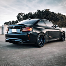 Load image into Gallery viewer, Black BMW M2 (F87) with aftermarket cs carbon fiber rear trunk spoiler and dark aftermarket wheels parked outdoors.